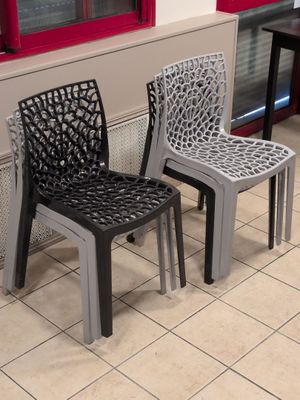 trois chaises en plastique placées les unes à côté des autres sur un sol carrelé