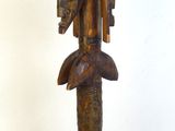 statue en bois représentant une femme avec un oiseau sur la tête, posée sur un socle