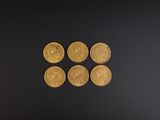 quatre pièces d'or posées les unes à côté des autres sur une surface noire