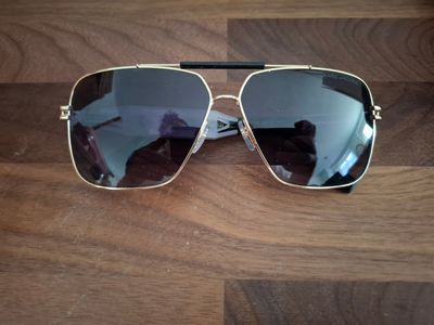 des lunettes de soleil posées sur une table en bois, avec un miroir en arrière-plan