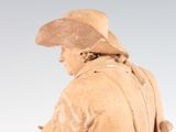 statue of a man in a hat and trench coat holding a rifle