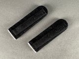 pair of black rubber grips with white pips on a gray surface