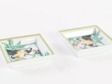 two small square dishes with birds painted on them