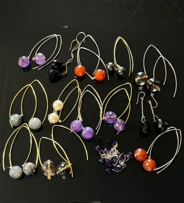 many pairs of earrings that are on a black surface