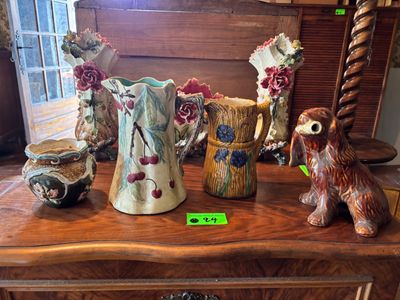 many vases sitting on a wooden table with a dog figurine