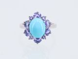 une pierre ovale de couleur turquoise, entourée de pierres de tanzane et de tanzane
