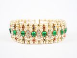 un gros plan sur un bracelet en or orné de perles vertes et blanches