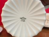 a person holding a small white plate on a table
