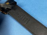 the black leather strap has a gold ring on it