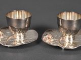pair of silverplated cups and saucers with flowers on them