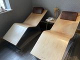 two lounge chairs in a room with a clock on the wall