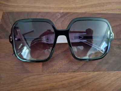 des lunettes de soleil posées sur une table en bois, avec une paire de lunettes par-dessus