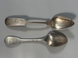 two silver spoons sitting next to each other on a table