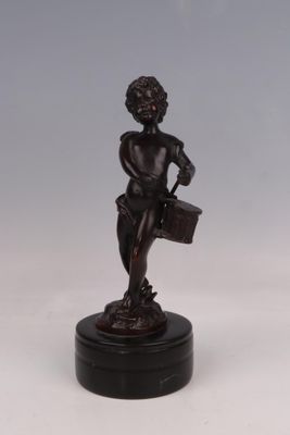 une figurine antique en bronze représentant un garçon tenant un panier