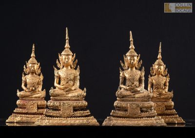 three gold statues of buddhas sitting on top of a black surface