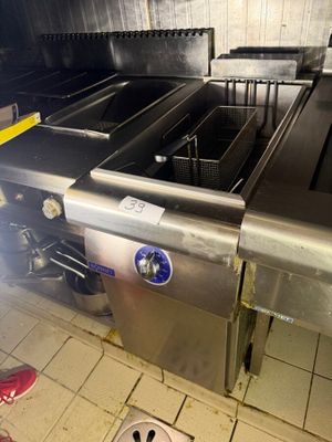 someone is standing in a kitchen with a fryer in the middle of the floor