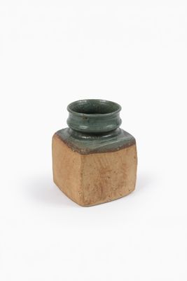 petit vase en céramique verte avec un socle en bois, posé sur une surface blanche