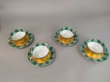four cups and saucers with green and white designs on them
