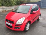 La petite voiture rouge est garée sur le parking.