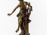 a bronze statue of a woman sitting on top of a table