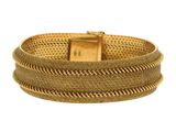 gros plan d'un bracelet en or sur fond blanc
