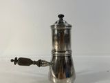 an antique silver coffee pot with a handle on a white surface