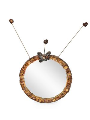 an image of a round mirror with a flower decoration on it