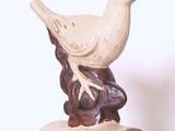 statue représentant un oiseau perché sur un rocher, posée sur un fond blanc