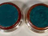 pair of silver and turquoise glass coasters on a white surface