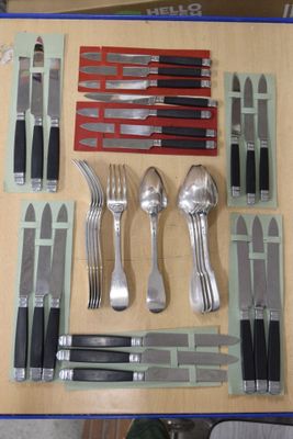 Des couteaux, des cuillères, des fourchettes et des couteaux sont disposés sur une table