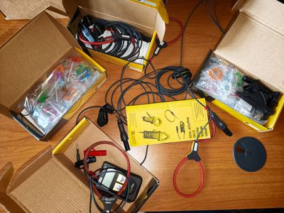 plusieurs boîtes contenant du matériel électronique posées sur une table, avec des câbles à n'en plus finir