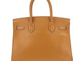 a tan leather handbag on a white background