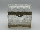 une boîte en argent et en verre munie d'une poignée, posée sur une surface blanche