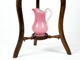 a pink vase sitting on a wooden stand
