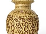 un vase jaune posé sur une surface blanche
