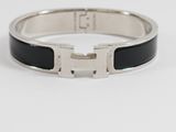 a close up of a black and silver bracelet on a white surface