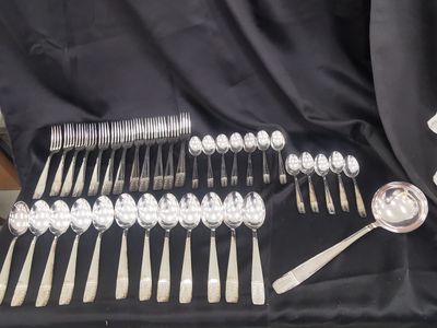 a lot of silverware on a table with a black cloth