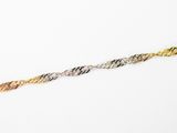 gros plan d'un bracelet en or et en argent sur une surface blanche
