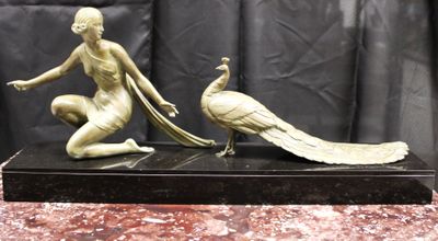 statue en bronze représentant une femme et un paon, posée sur un socle en marbre