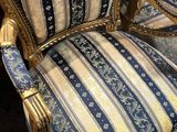 une chaise dorée dont l'assise est recouverte d'un tissu rayé bleu et blanc