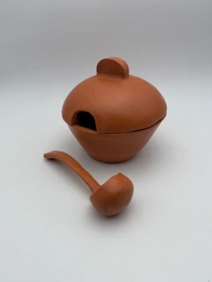 a small clay teapot with a wooden spoon in it