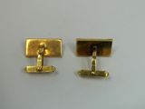 two pairs of gold cufflinks on a white surface