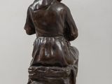 statue of a woman sitting on a rock with a hood over her head