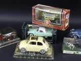 four toy cars are sitting in a display case on a black surface