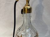 une bouteille en verre avec une poignée noire et un pinceau noir
