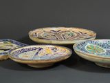 four ceramic bowls with designs on them sitting on a table