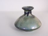 a small blue vase sitting on a white surface