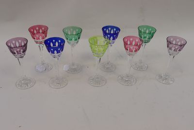six different colored wine glasses lined up on a white surface