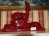 une statue rouge représentant un cerf, exposée devant un tableau