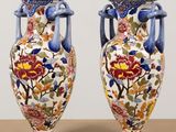 two vases with floral designs on them sitting on a table
